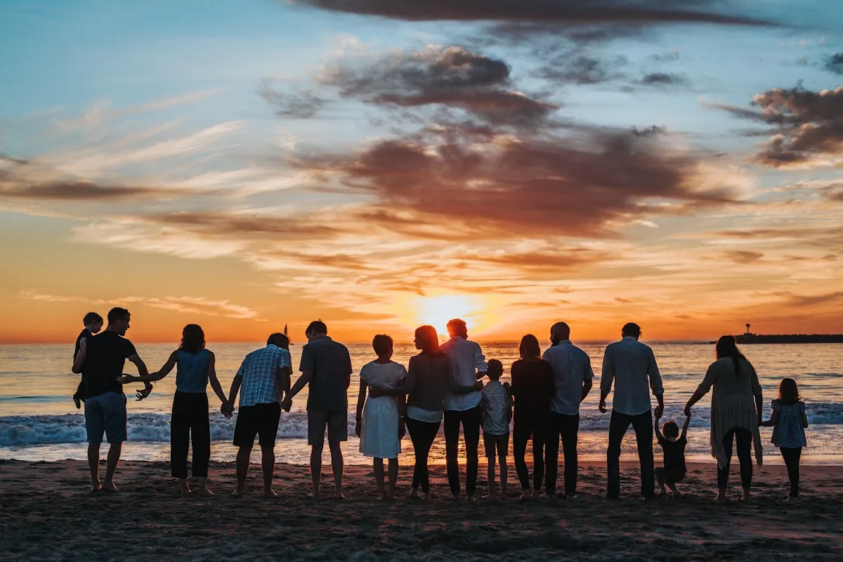 Une grande famille réunie au coucher du soleil sur une plage, le genre de moment précieux qu'il vaut la peine de transformer en portrait commémoratif